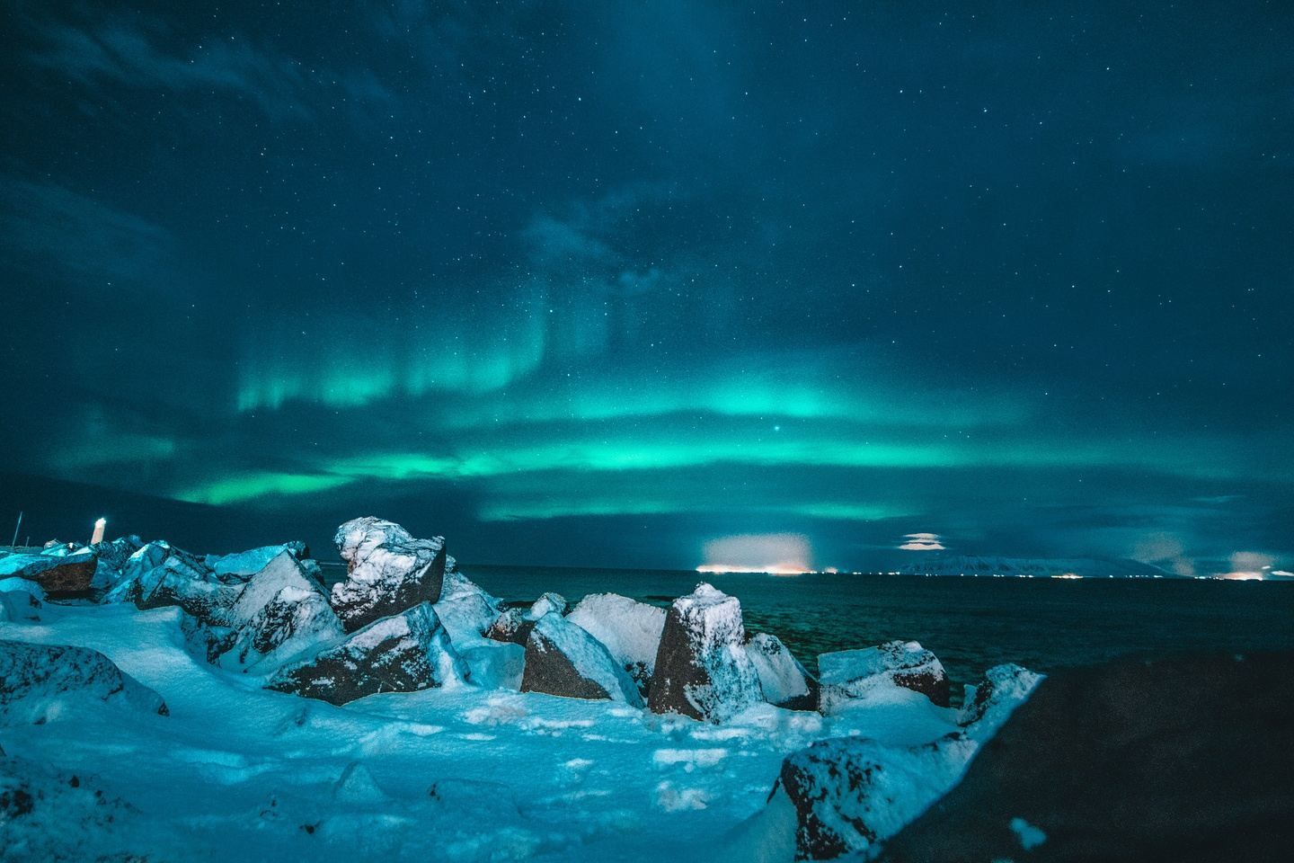 The aurora borealis is shining over the ocean at night.