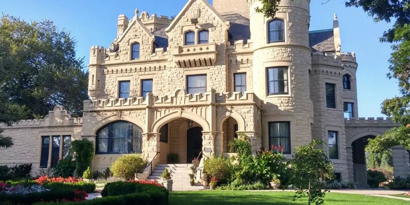 A large castle shaped building with a lot of windows is surrounded by trees and bushes.