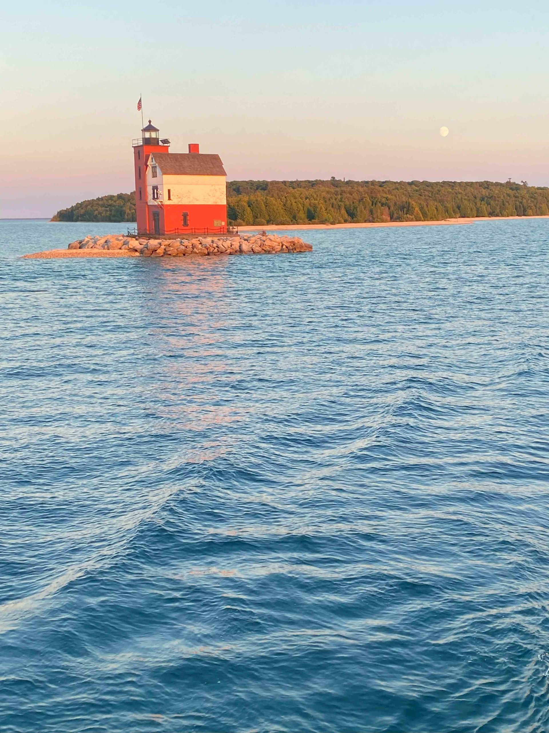 A lighthouse on a small island in the middle of a body of water