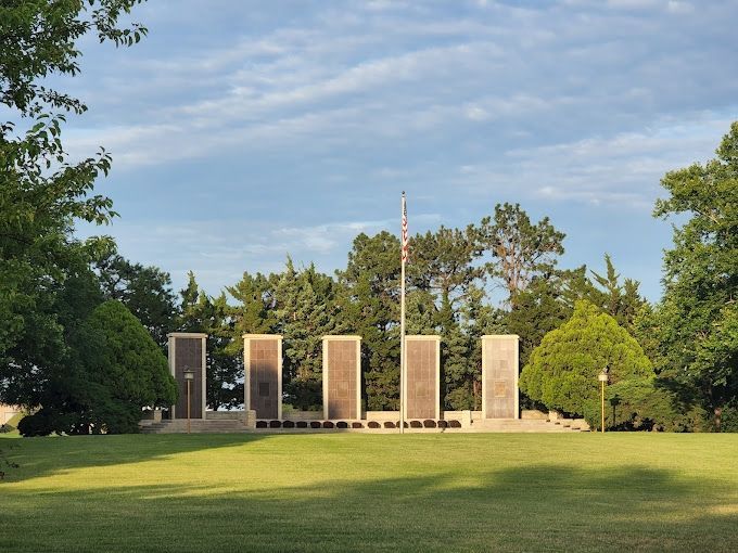 A memorial in the middle of a grassy field with trees in the background