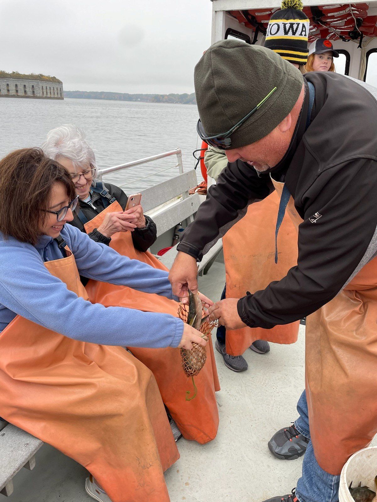 A group of people are sitting on a boat looking at a crab.