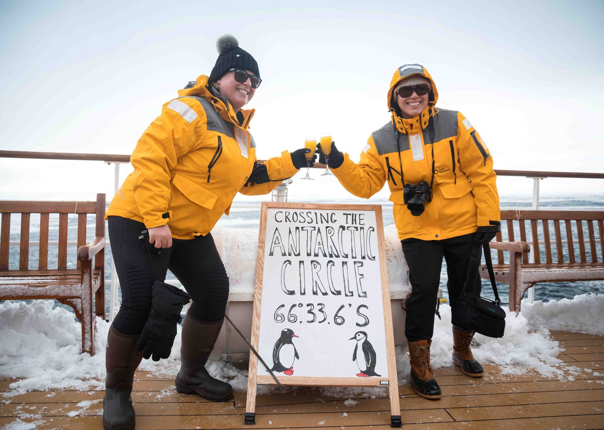 Two women are standing next to a sign that says genuine antarctica cruise