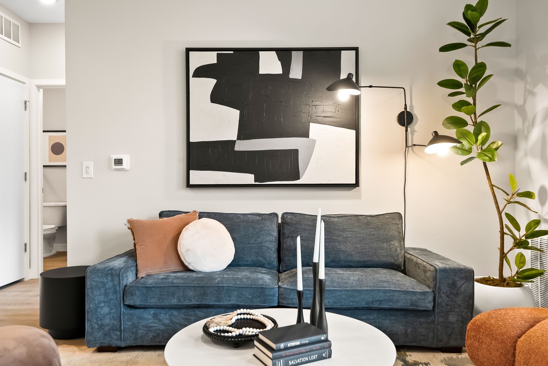 A living room with a couch , coffee table , and painting on the wall Origin Apartments.