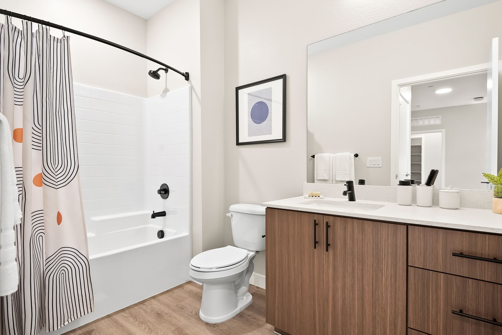 A bathroom with a toilet, sink, bathtub and mirror at Origin, which offers apartments for rent in Goodyear, AZ.