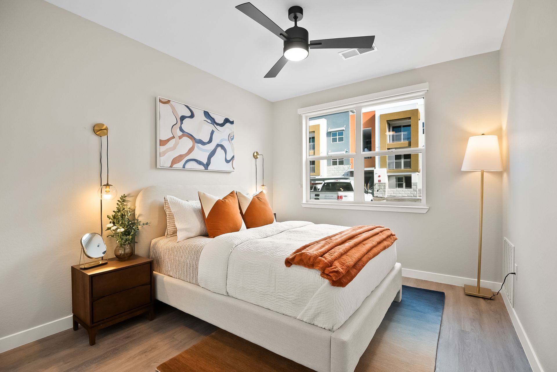 A bedroom with a bed , nightstand , lamp and ceiling fan Origin Apartments.