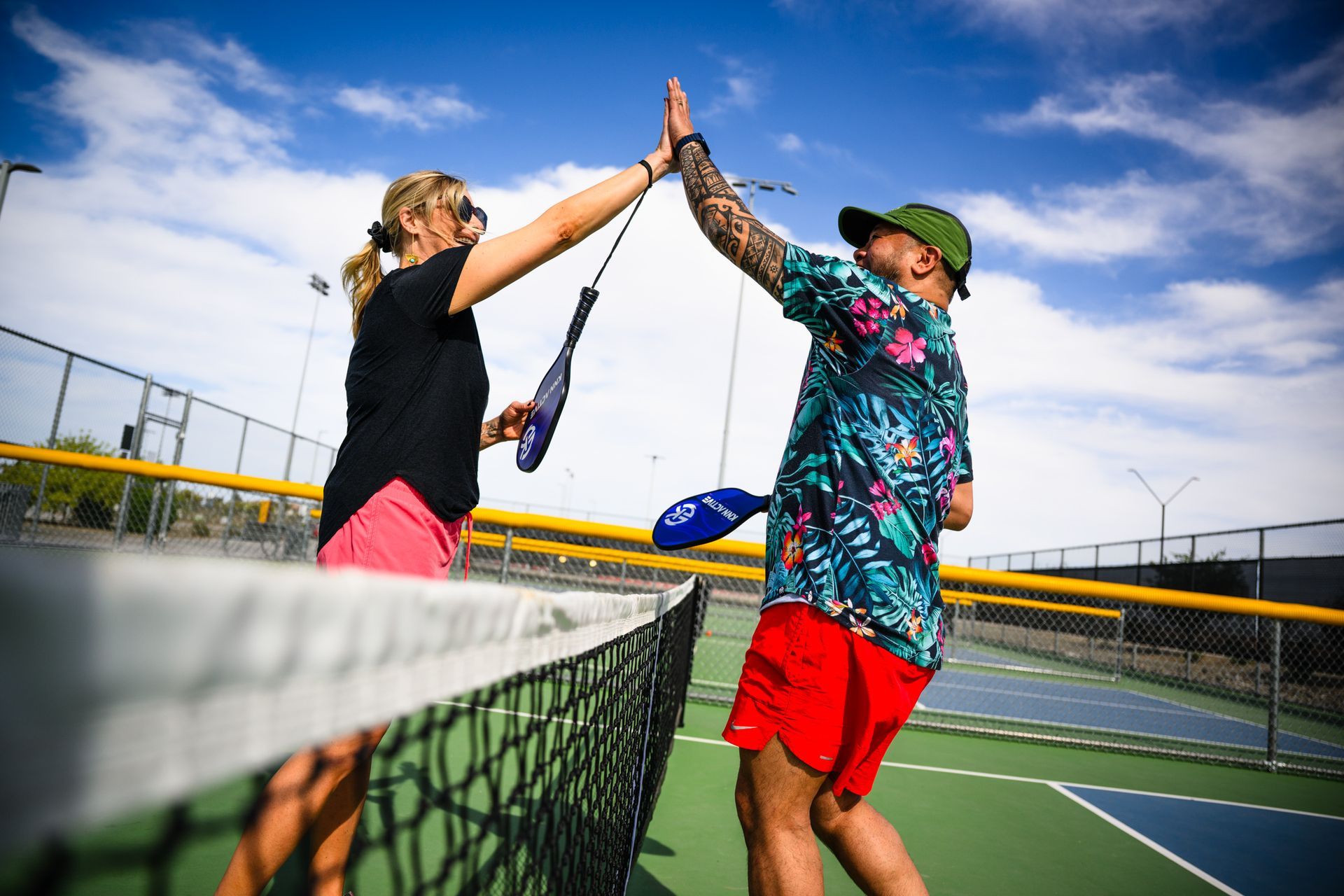 A man and a woman are giving each other a high five on a tennis court.