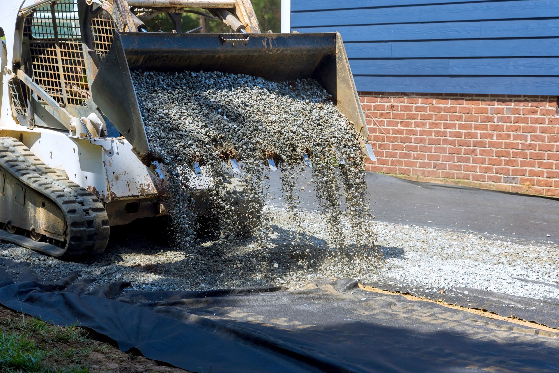 A bulldozer is loading gravel into a driveway.
