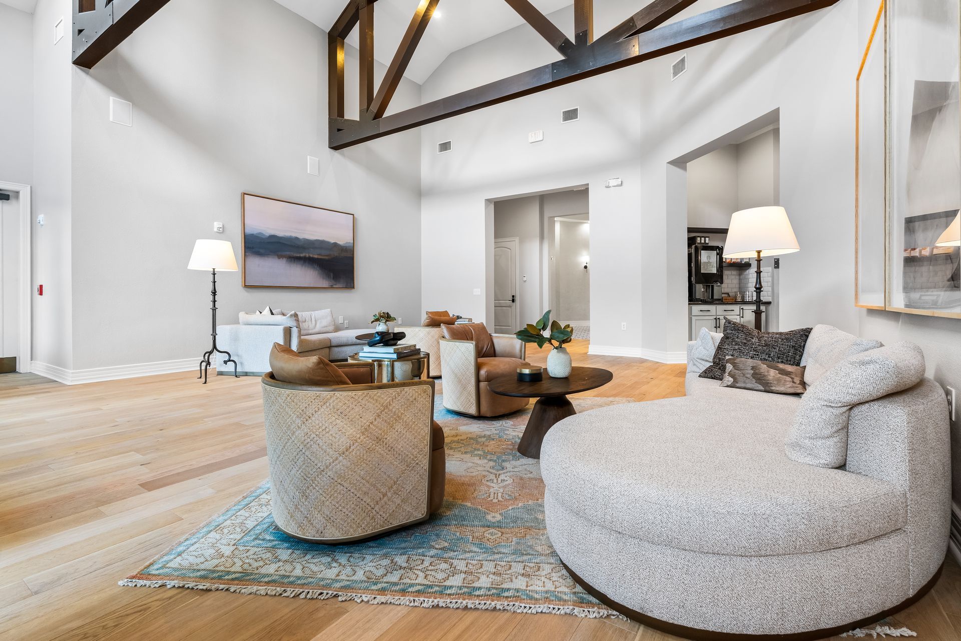 A living room with a couch, chairs, a coffee table and a painting on the wall.