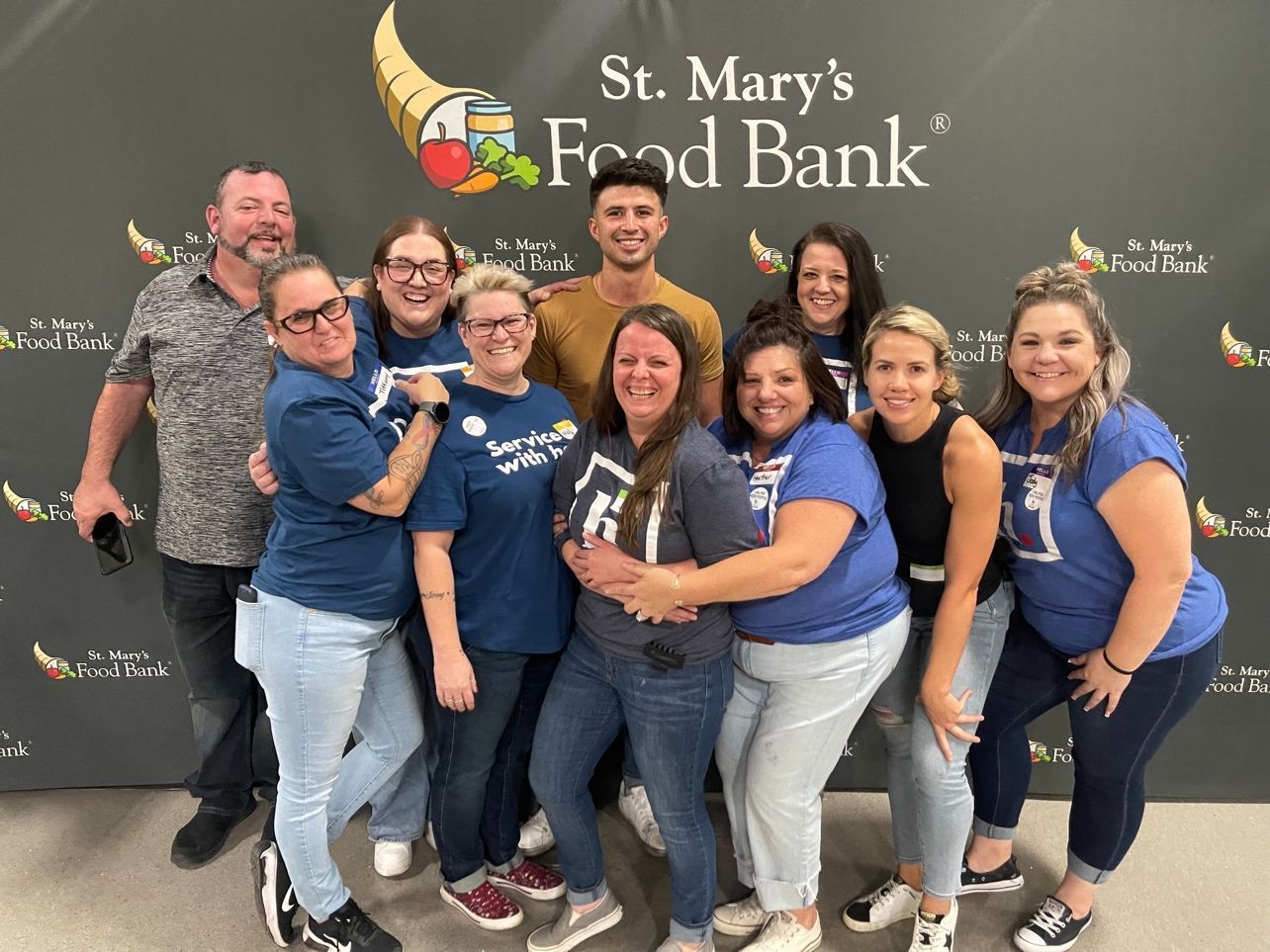 A group of people are posing for a picture in front of a sign that says st. mary 's food bank.