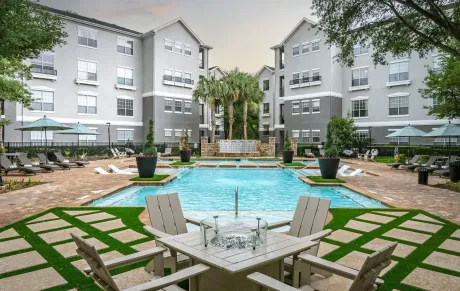 A large swimming pool with a table and chairs in front of a building.