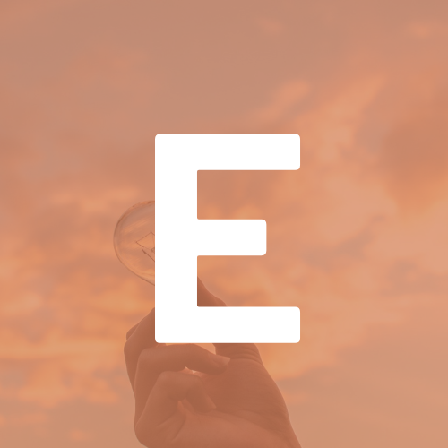 A person is holding a light bulb in front of the letter e.