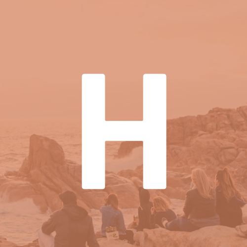 A group of people are sitting on rocks on a beach.