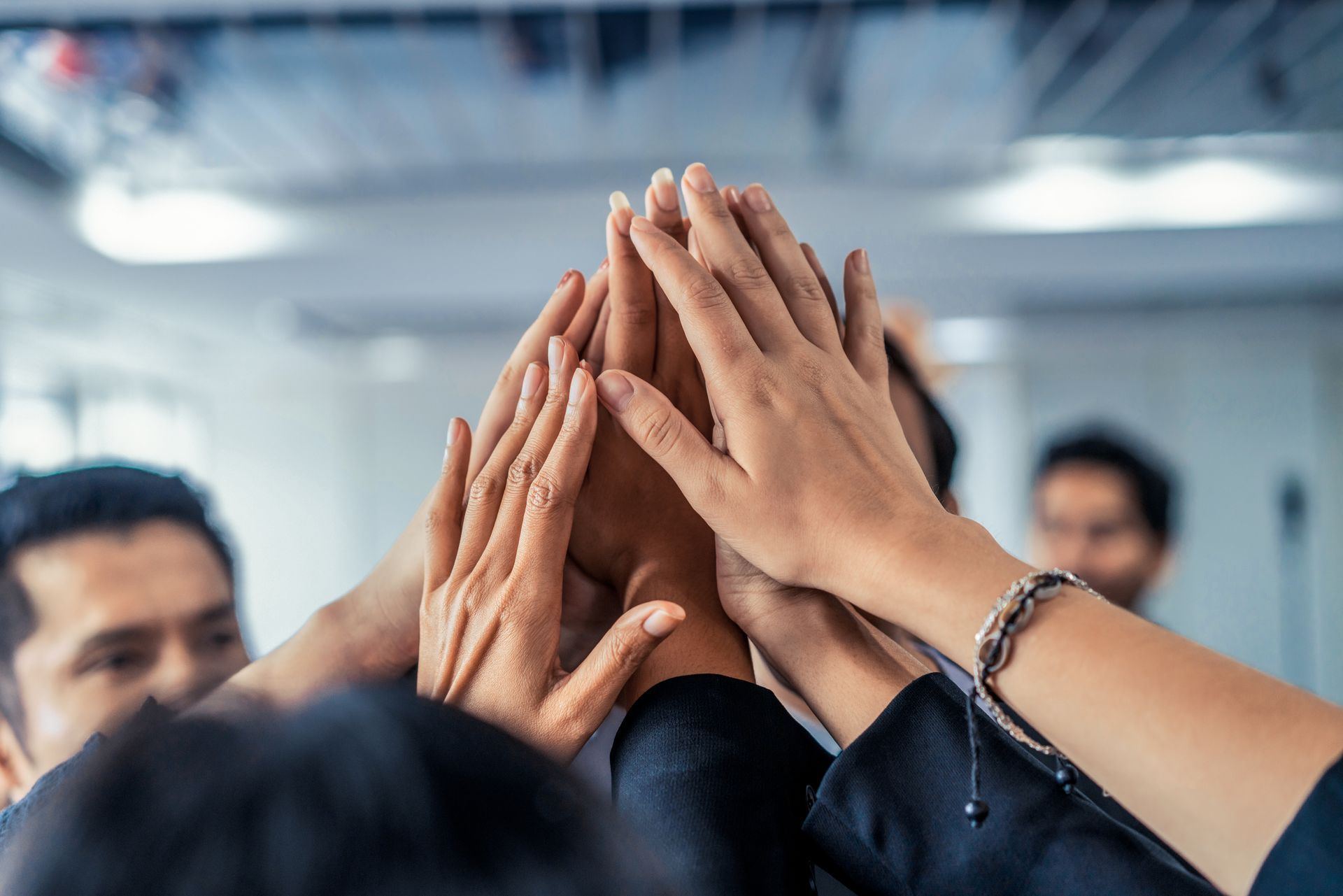 A group of people are putting their hands together in a huddle.