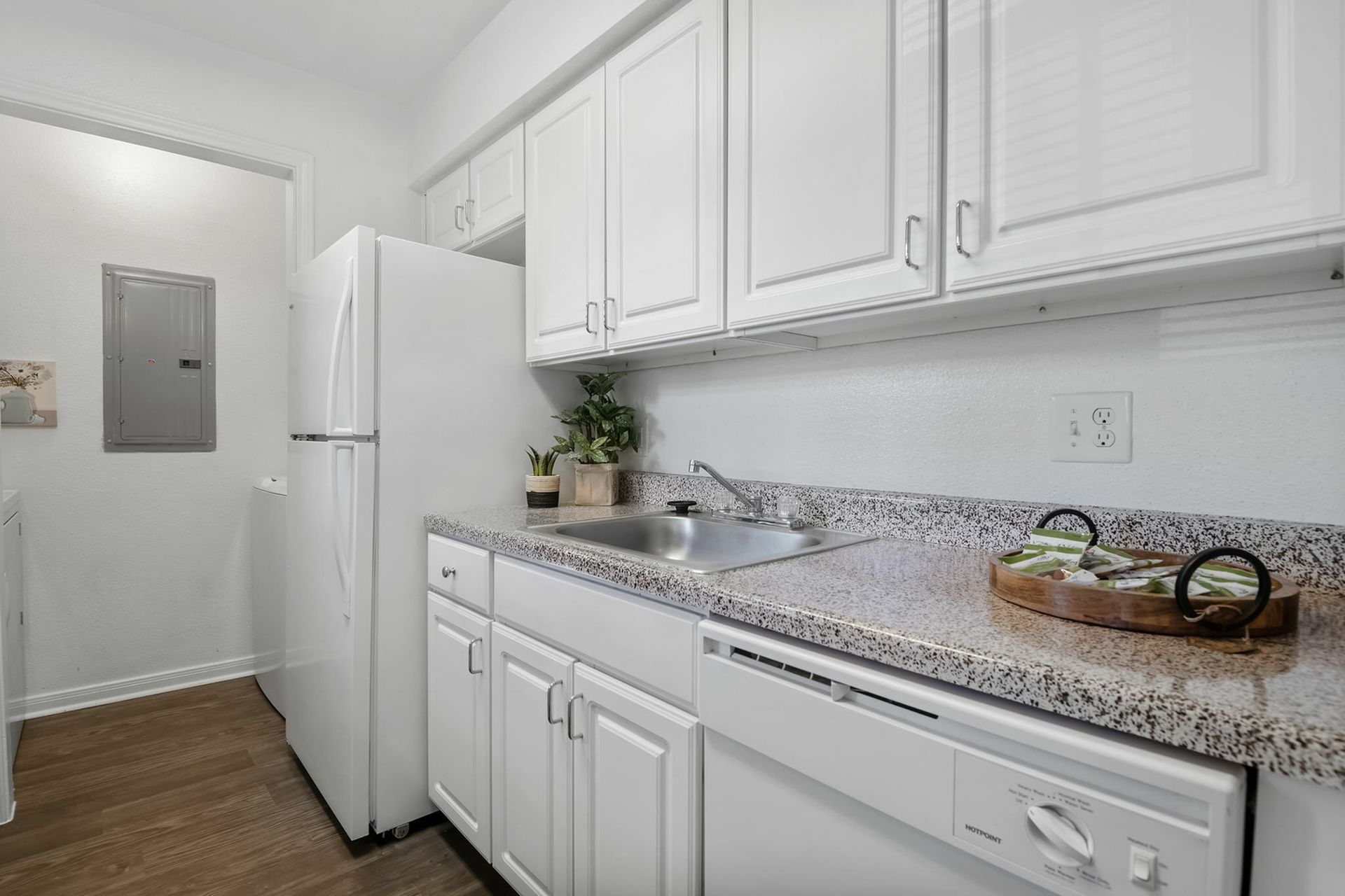 White kitchen with granite countertops, sink, fridge, and dishwasher.