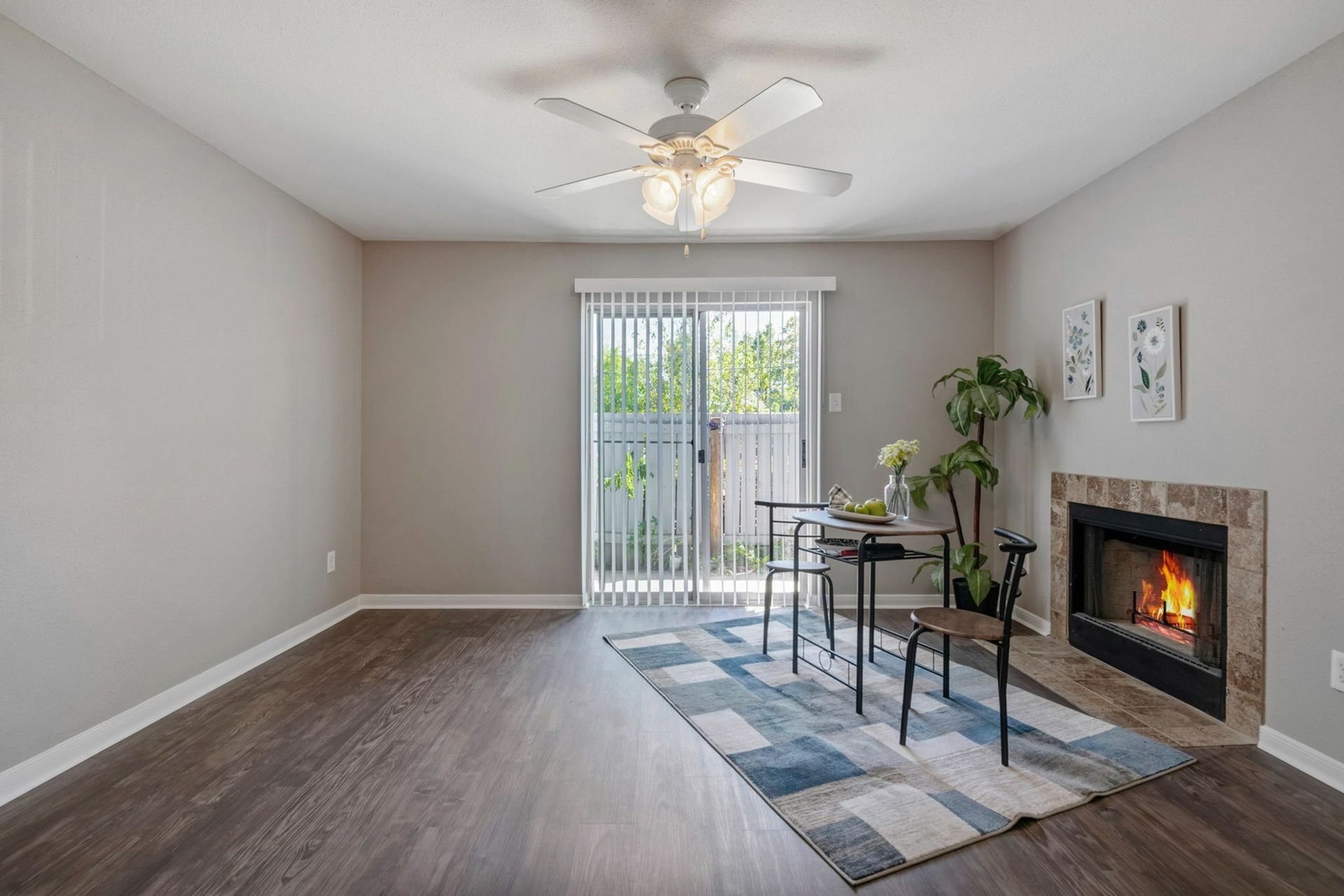Living room with a fireplace, ceiling fan, wood flooring, and a sliding glass door to outdoors.