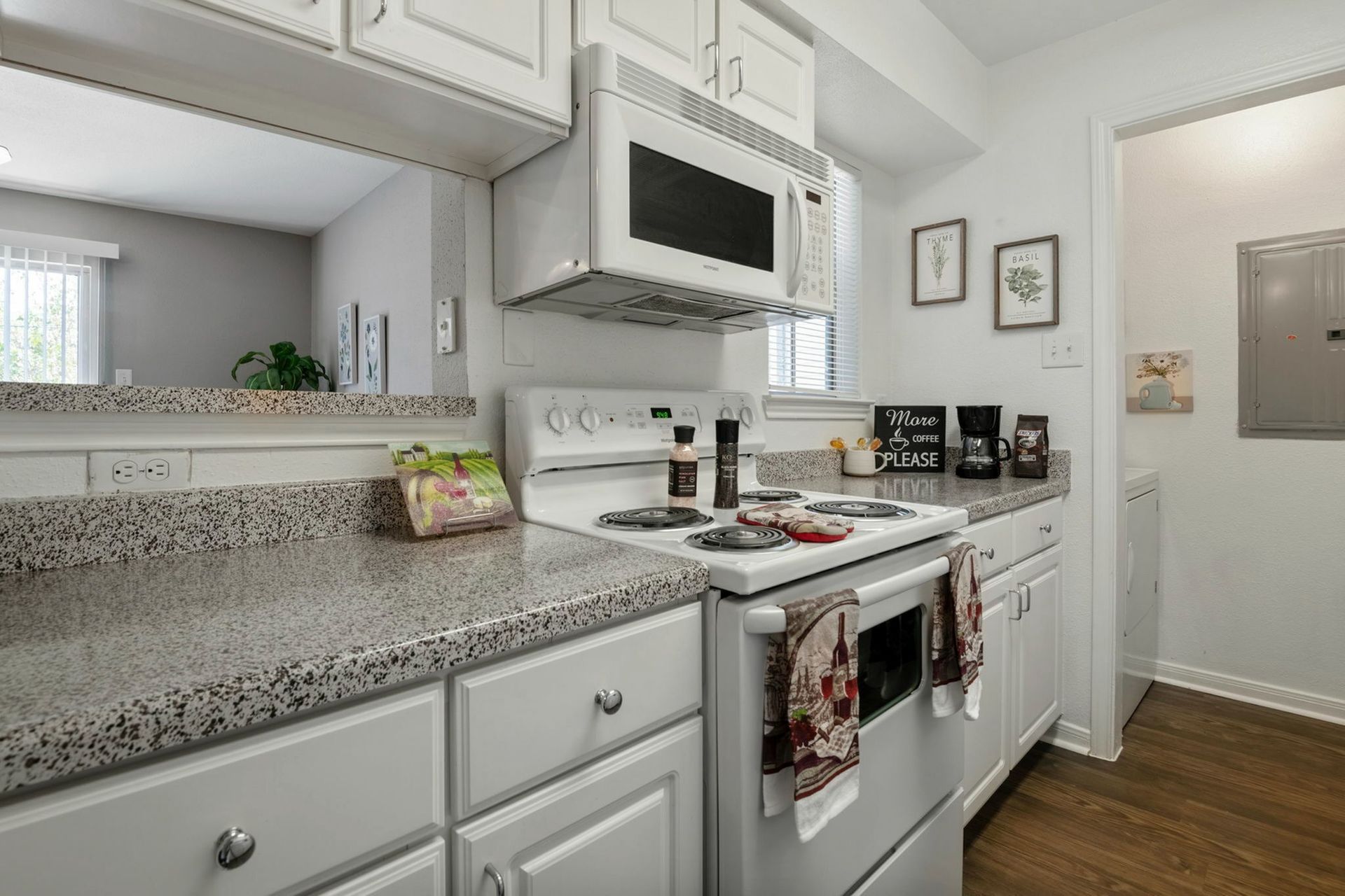 White kitchen with stove, microwave, granite counters, and white cabinets.
