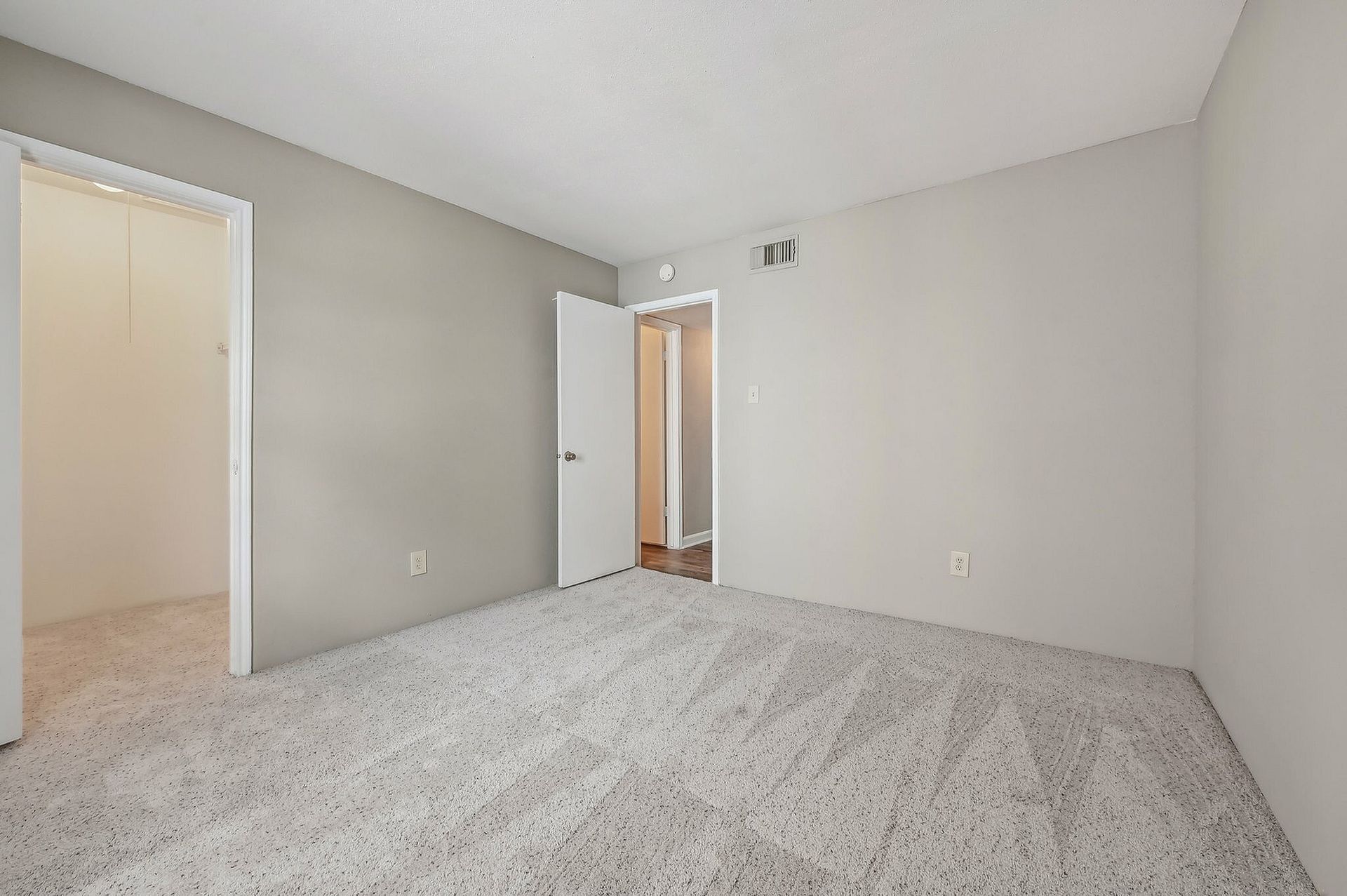 Empty bedroom with gray walls, white door, and light carpet.