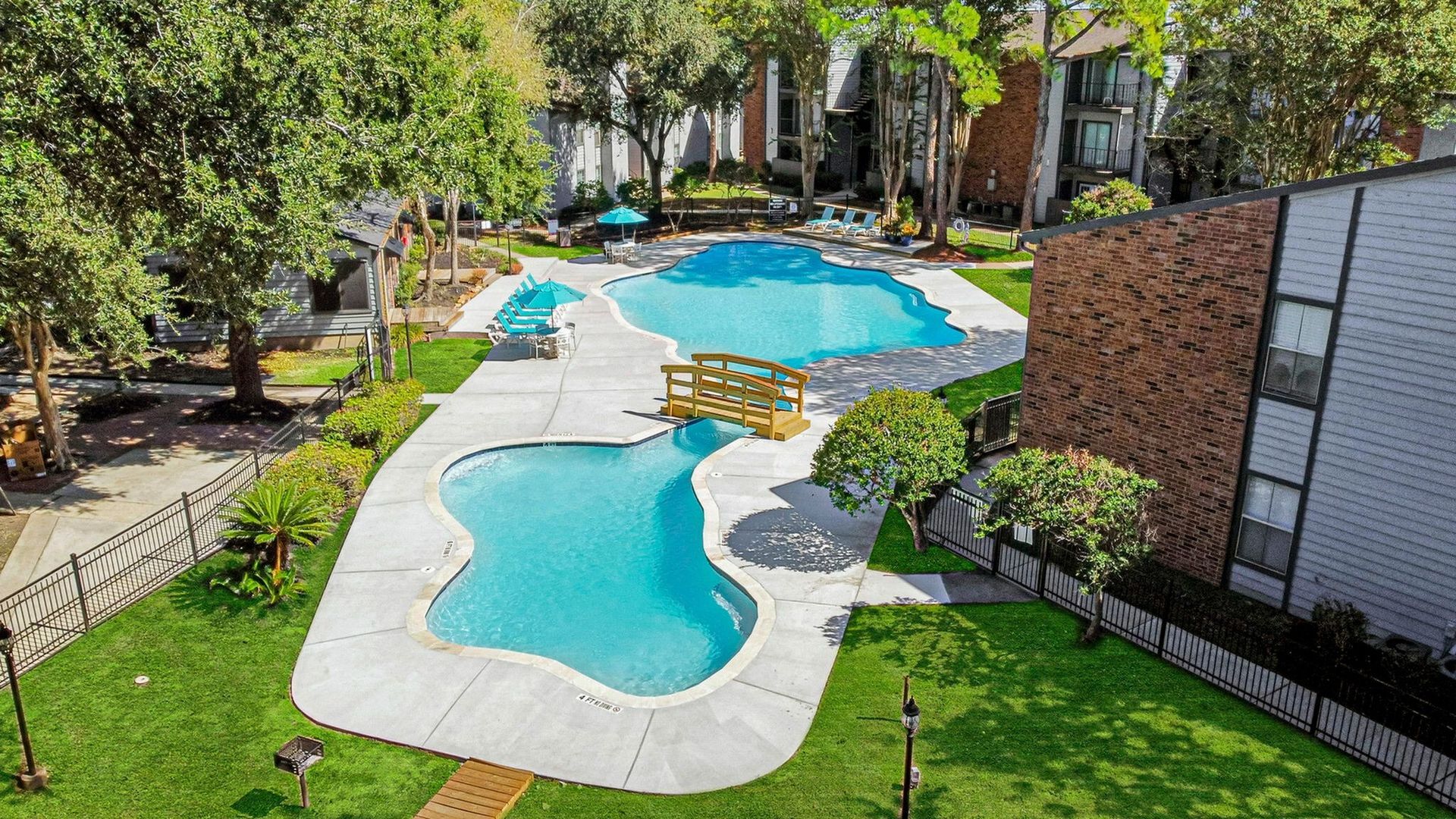 Aerial view of a winding outdoor pool in a residential complex with lounge chairs.
