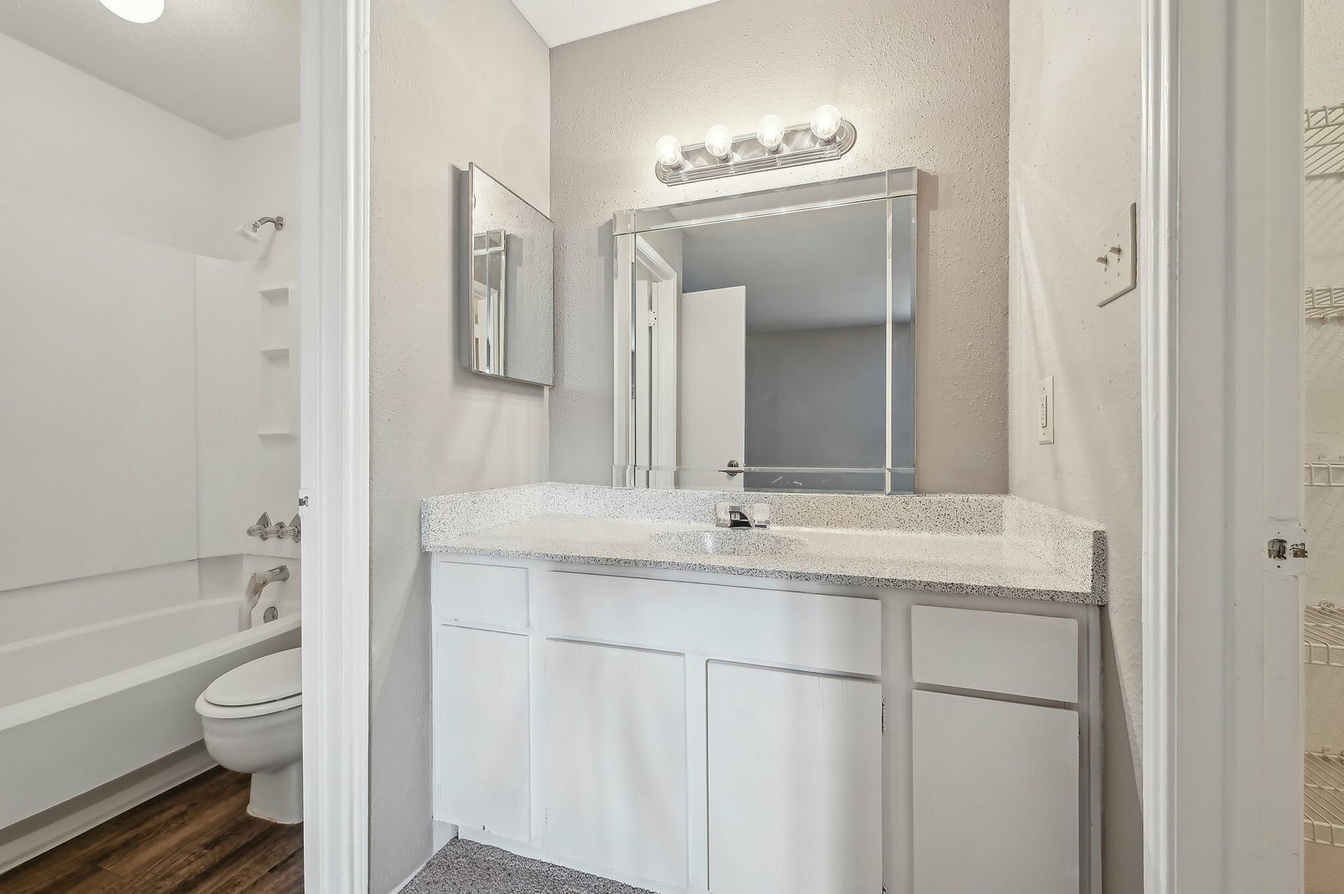 Bathroom with white vanity, mirror, toilet, and tub/shower combo.