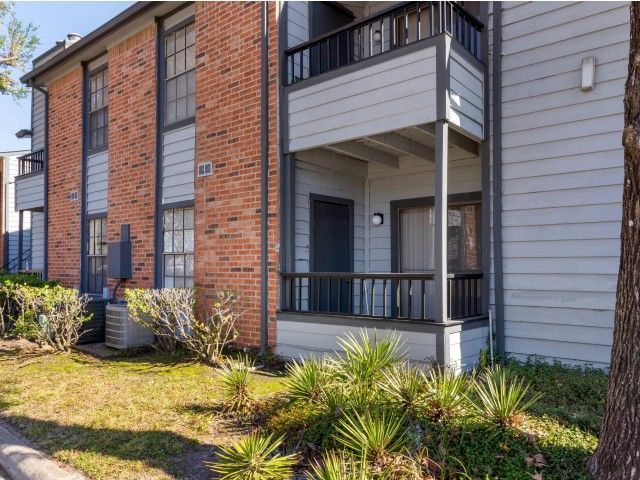 Exterior view of a multi-unit apartment building with balconies and landscaped yard.