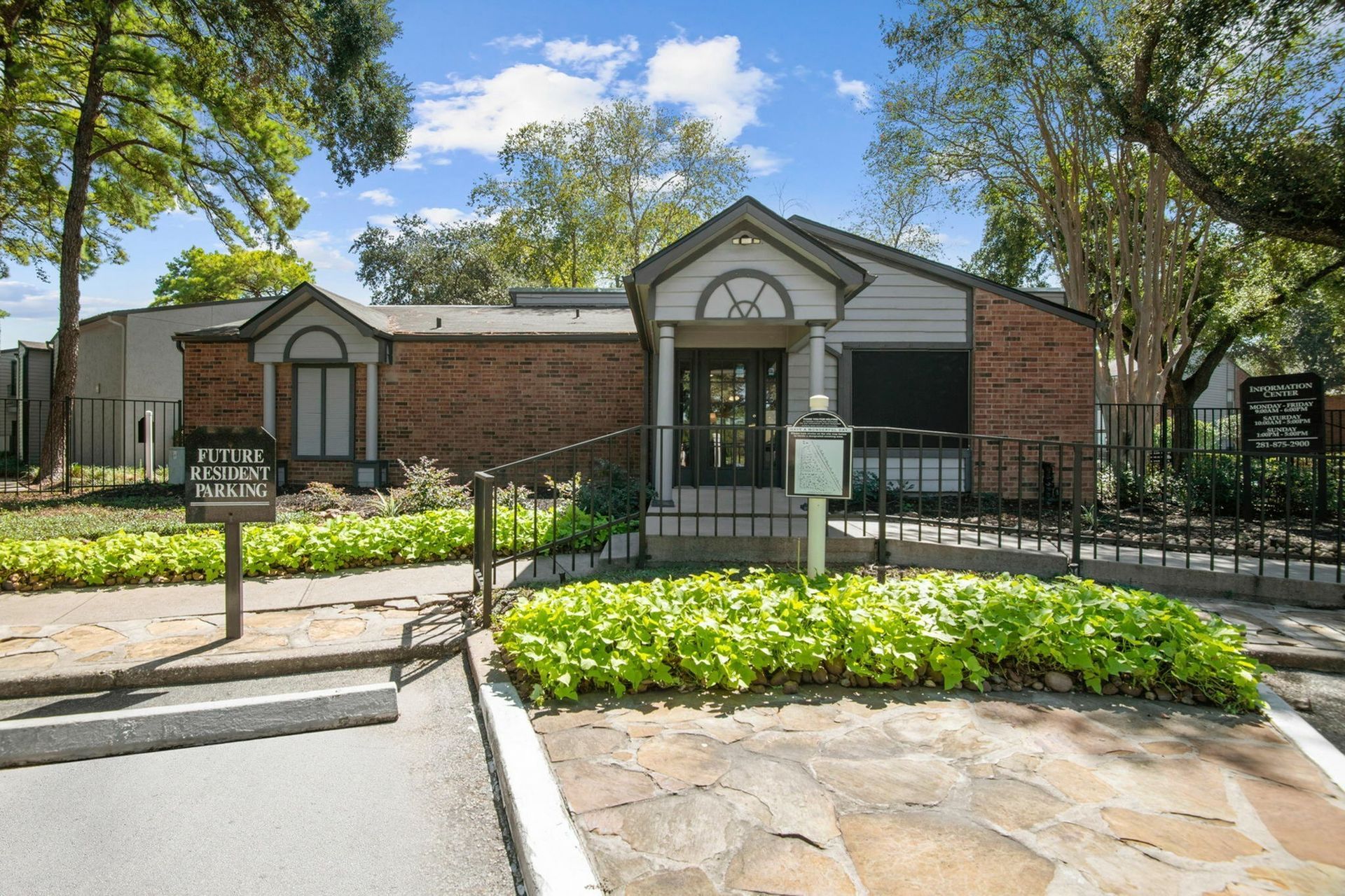 Brick leasing office with arched window, front entrance, and manicured landscaping.