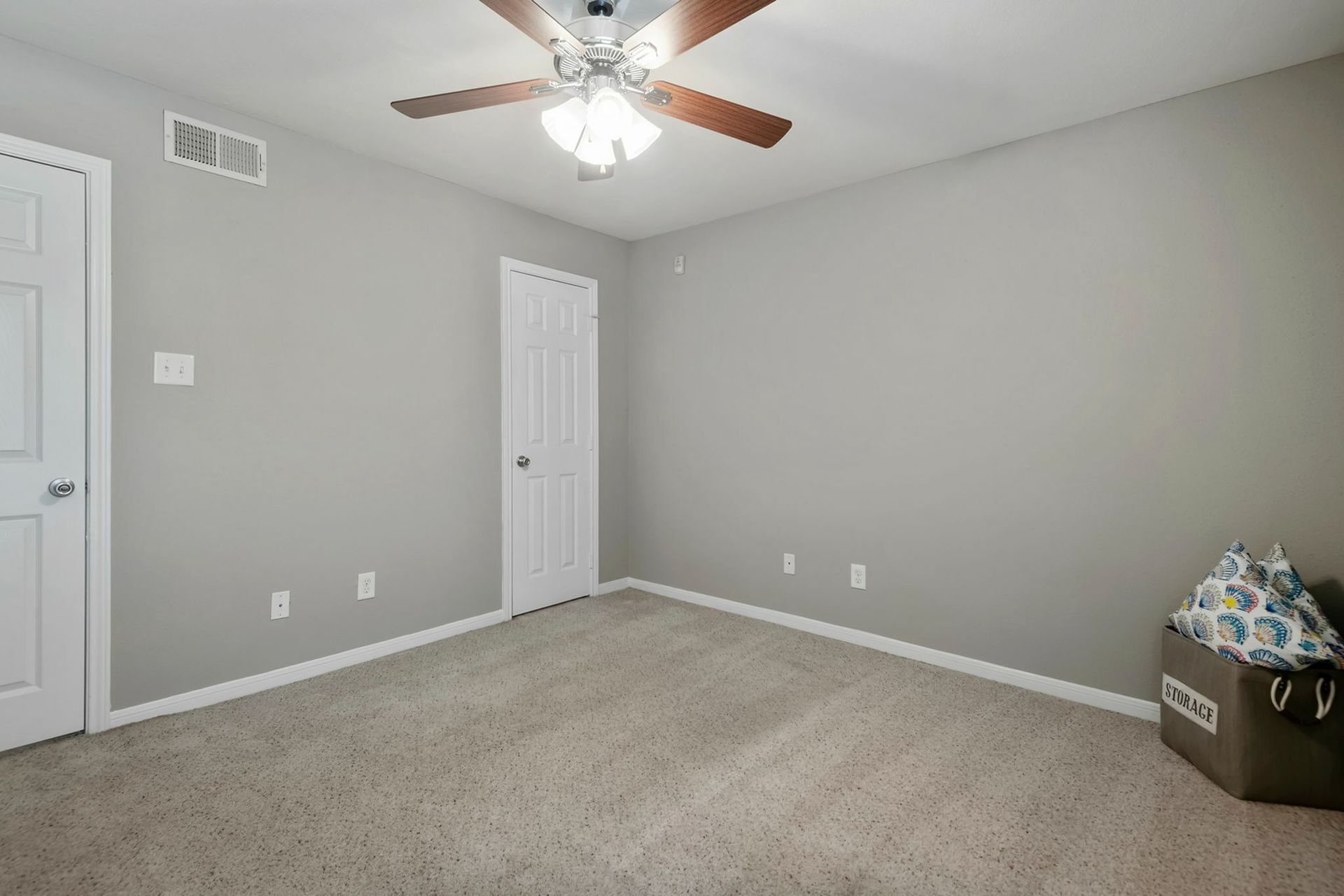 Bedroom in an apartment with gray walls, a ceiling fan, and beige carpet.