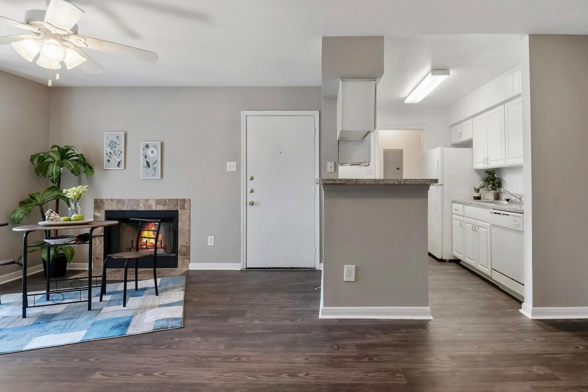 Living room with fireplace, dining area, and open kitchen; gray walls, dark wood floor at Driscoll Place in Houston, TX.