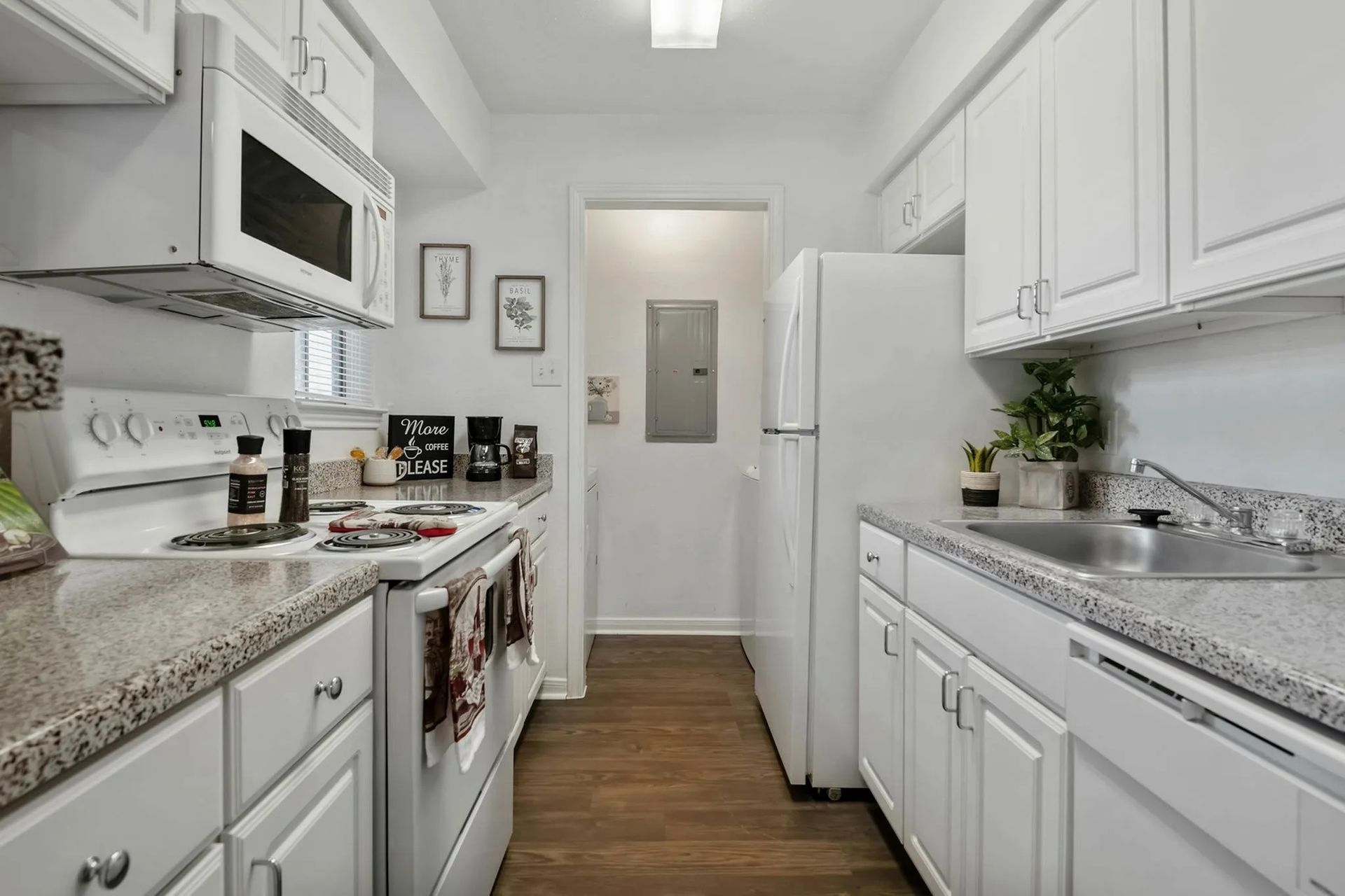 White kitchen with appliances, cabinets, and countertops; view down a hallway at Driscoll Place in Houston, TX.