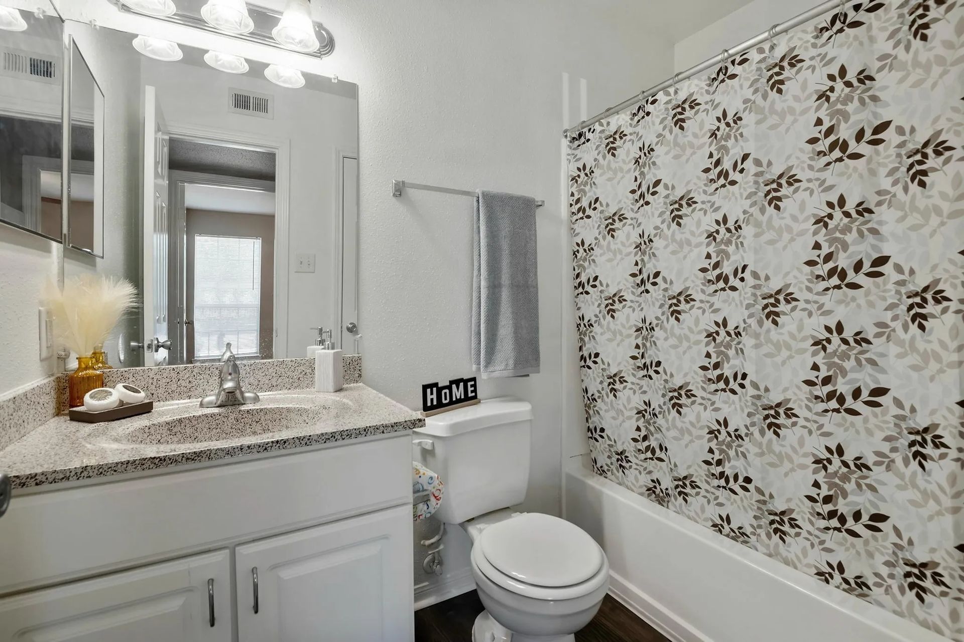 Bathroom with white vanity, floral shower curtain, and gray towel at Driscoll Place in Houston, TX.