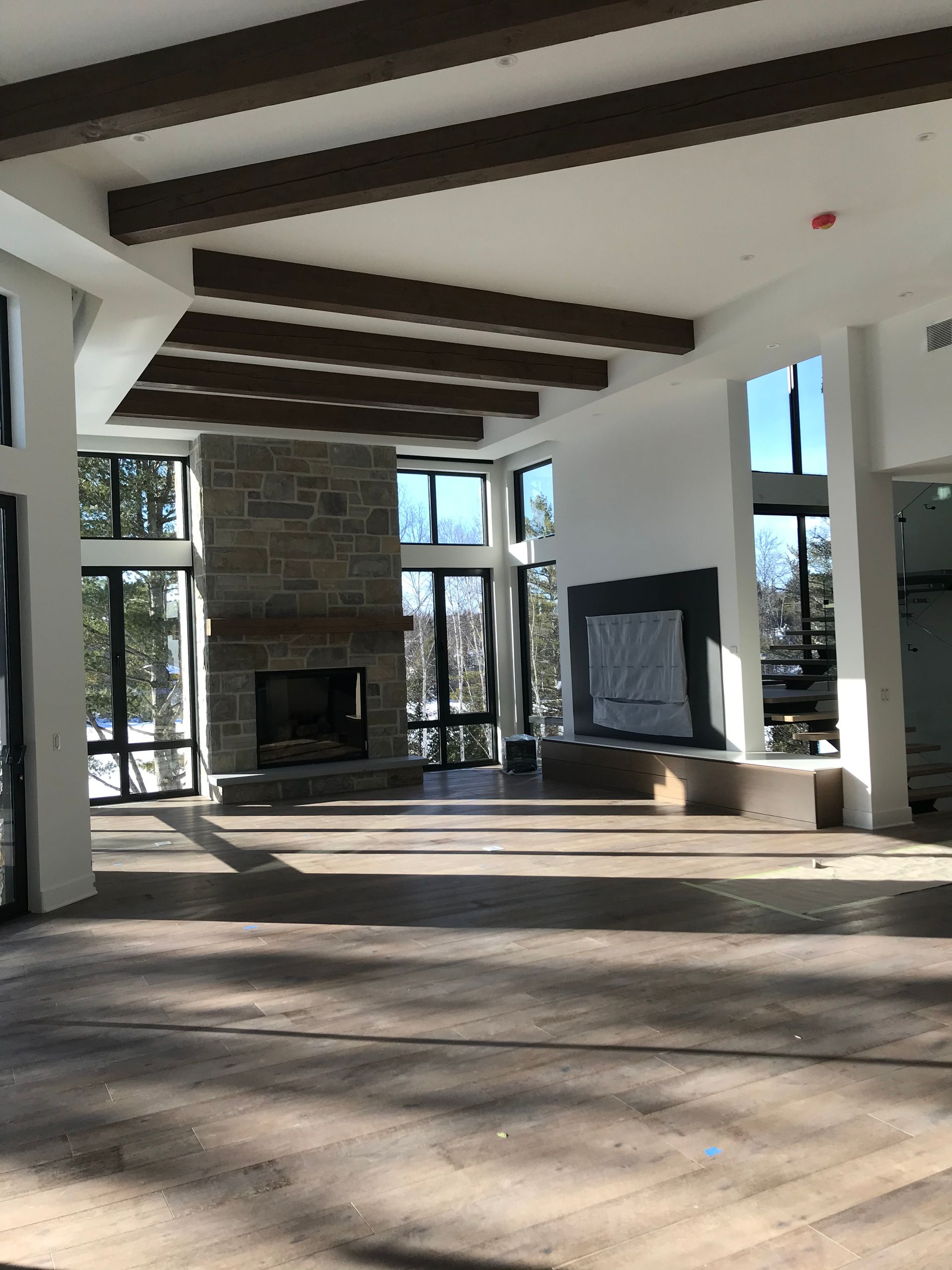 Pièce spacieuse avec de grandes fenêtres, une cheminée et des poutres apparentes.