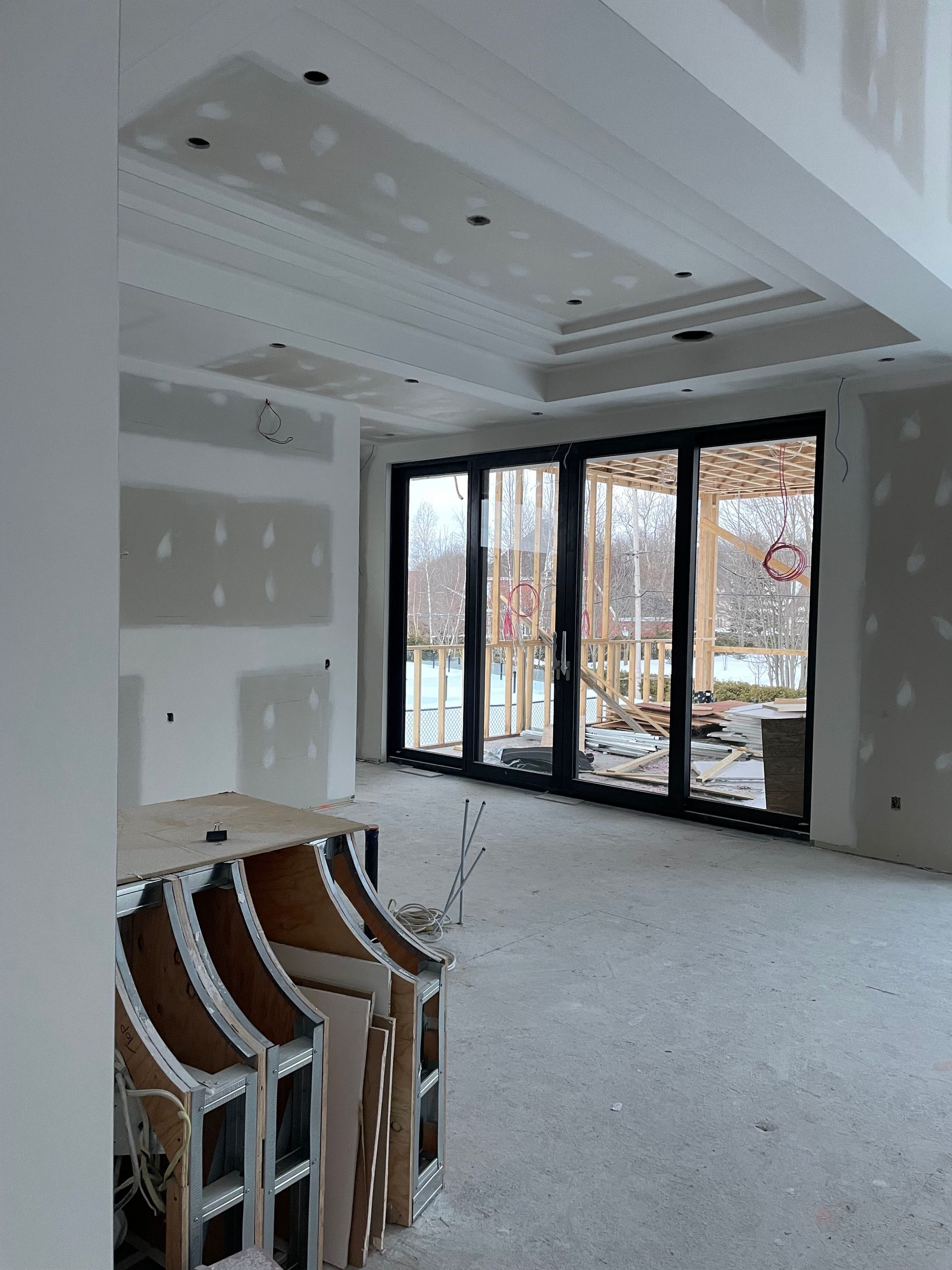 Intérieur en cours d'aménagement avec cloisons sèches, portes coulissantes noires et plafond décoratif.