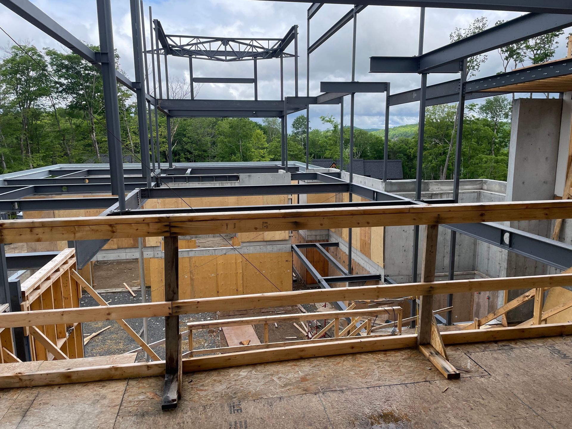 Bâtiment à ossature métallique en construction, garde-corps en bois au premier plan.