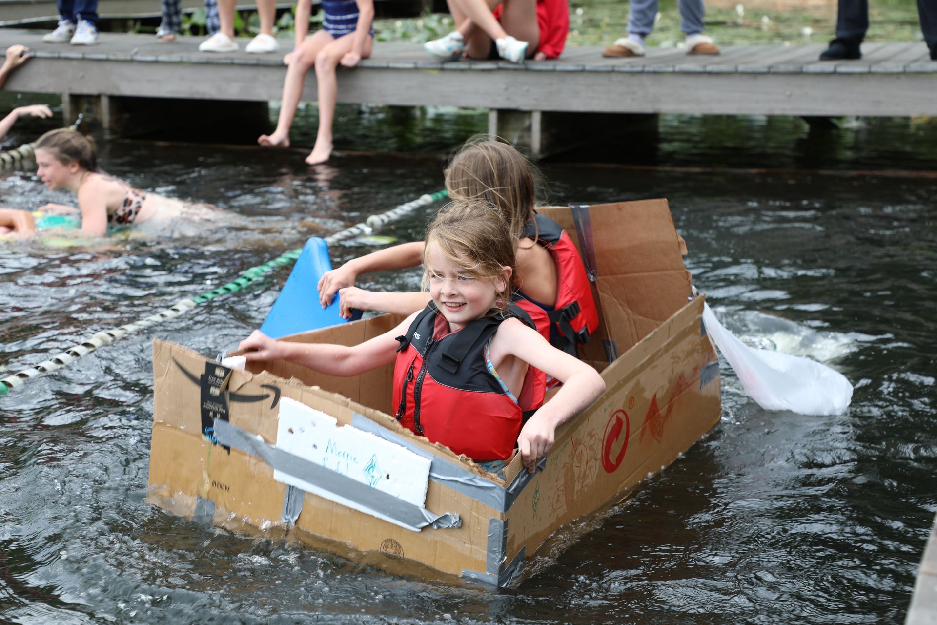A person with a smiling expression swings on a green playground swing set in a grassy park.
