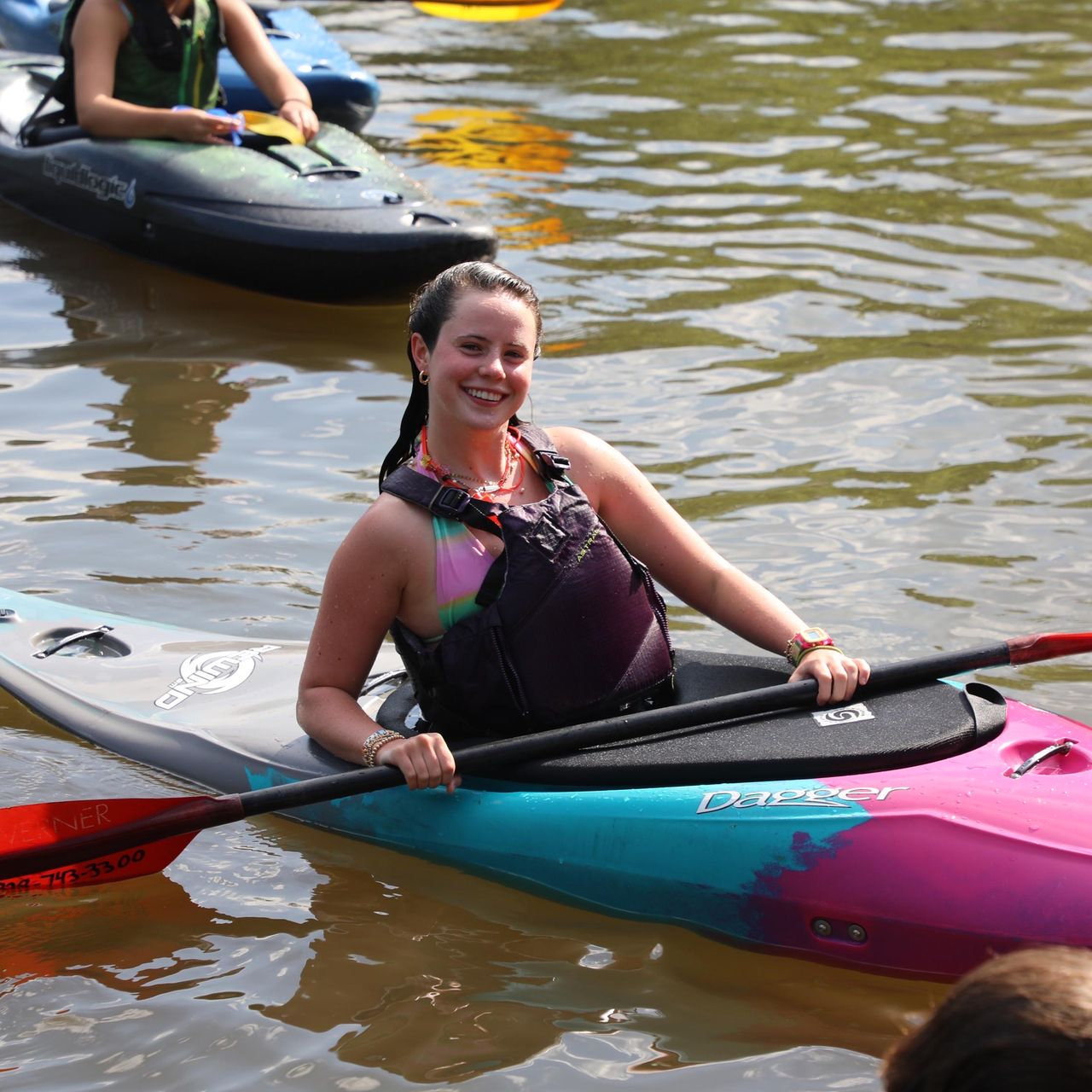 A smiling person wearing glasses and a 