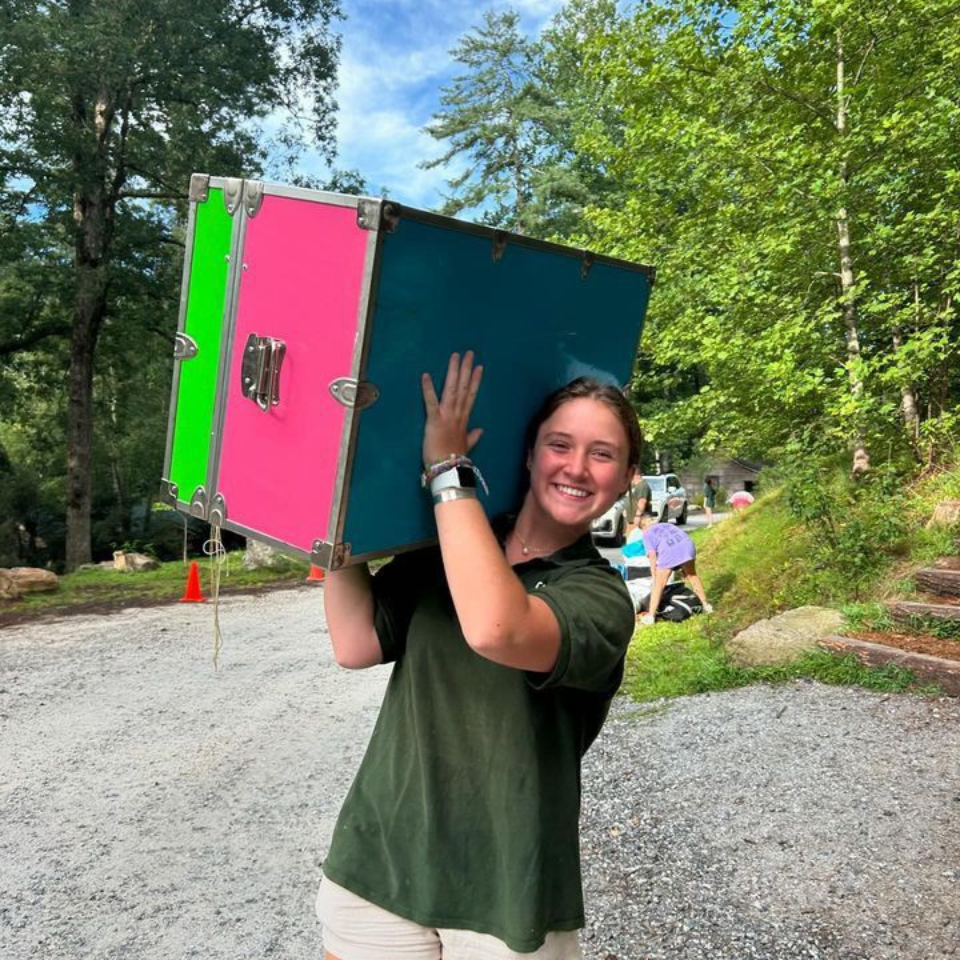 A smiling person wearing glasses and a 