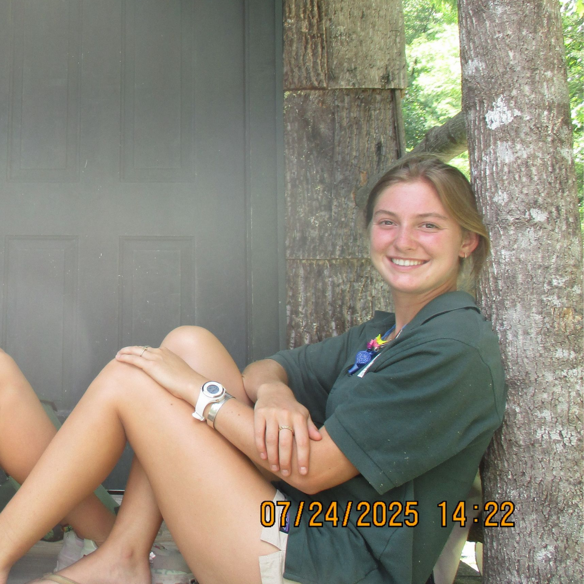 A smiling person wearing glasses and a 