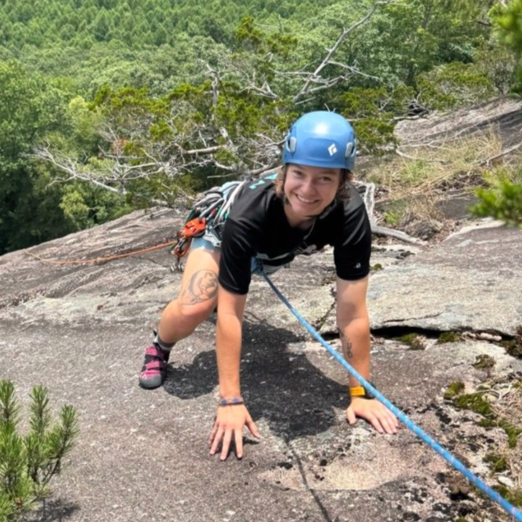 A smiling person wearing glasses and a 