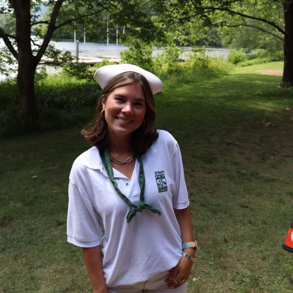 A smiling person wearing glasses and a 