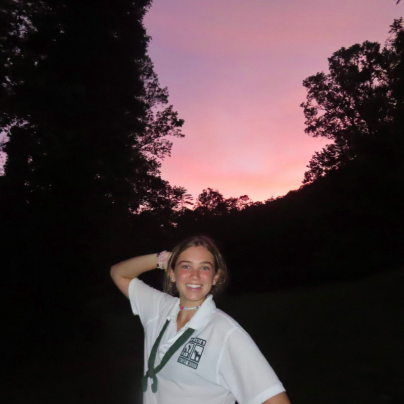 A smiling person wearing glasses and a 