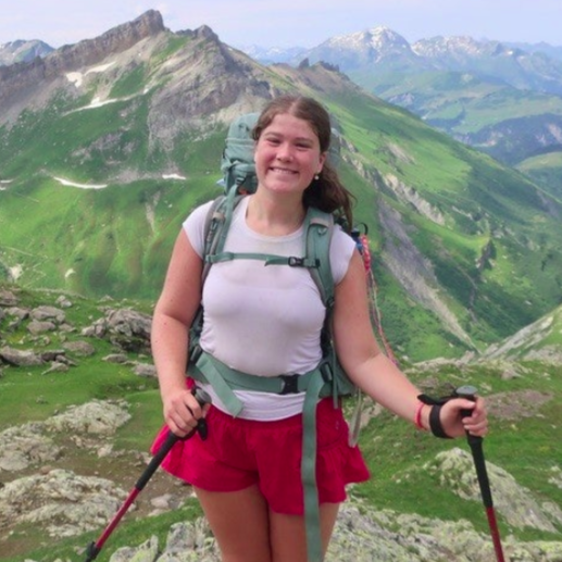 A smiling person wearing glasses and a 