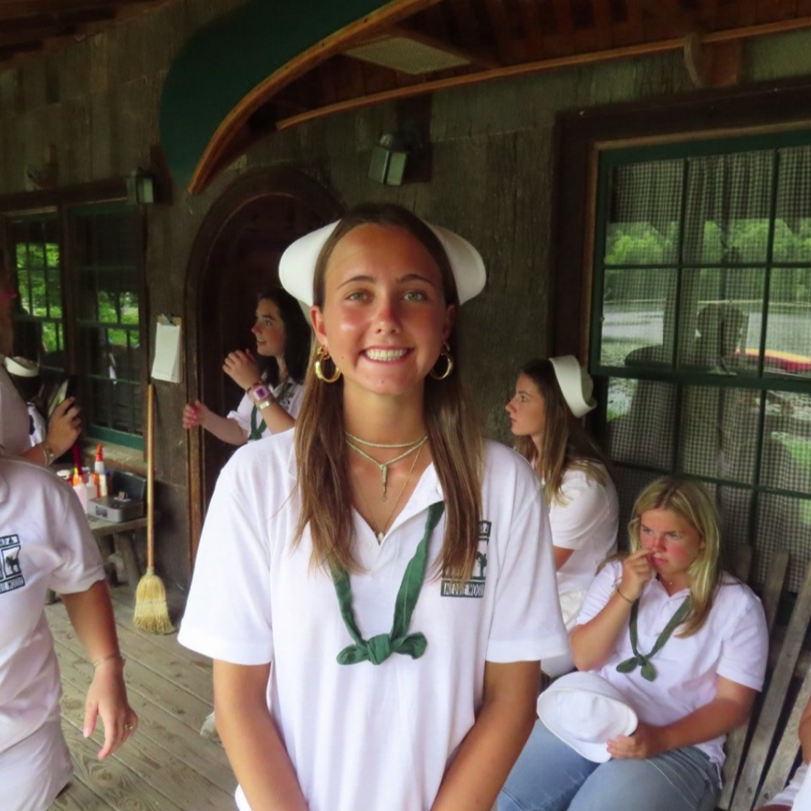 A smiling person wearing glasses and a 