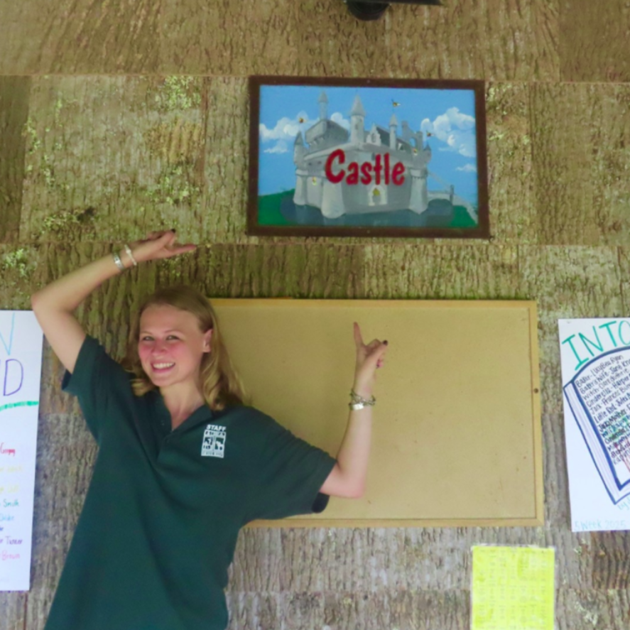 A smiling person wearing glasses and a 