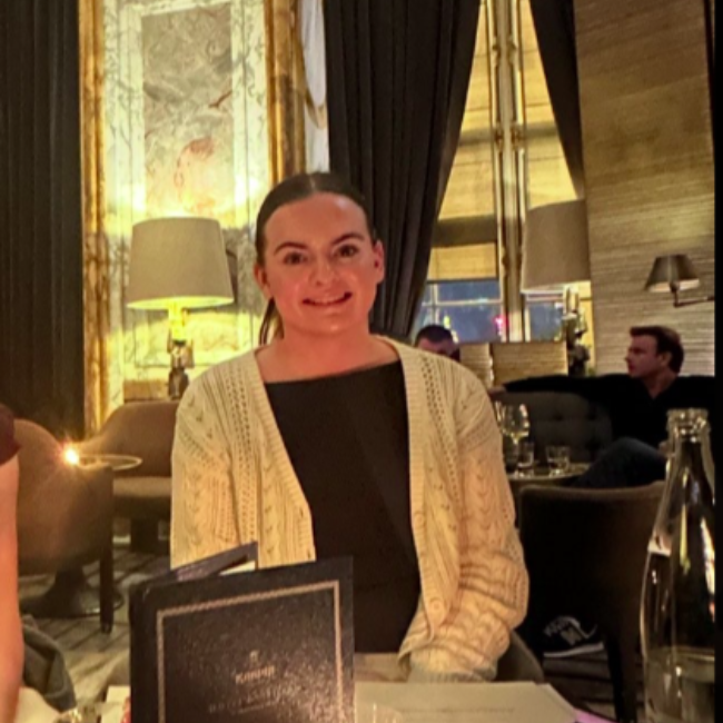 A smiling person wearing glasses and a 