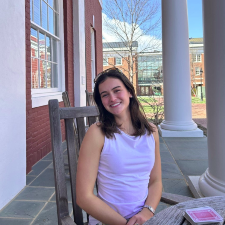 A smiling person wearing glasses and a 