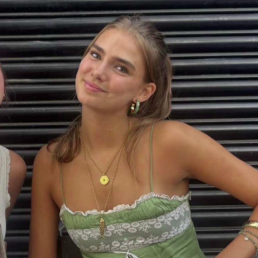 A smiling person wearing glasses and a 