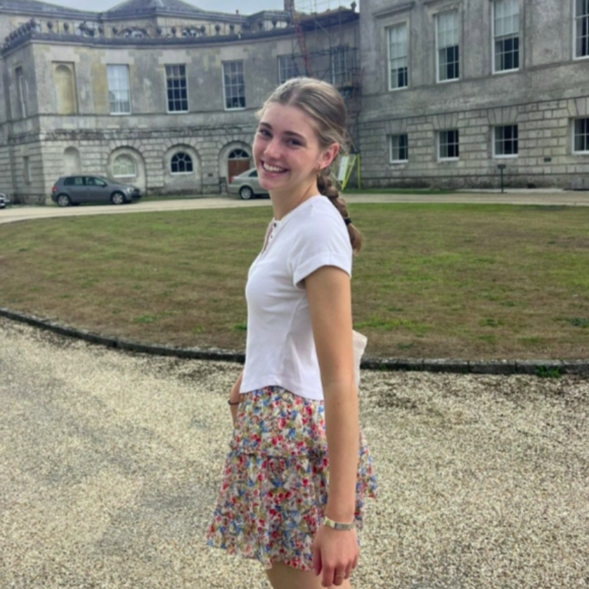 A smiling person wearing glasses and a 