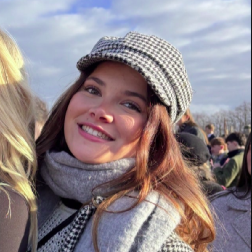 A smiling person wearing glasses and a 