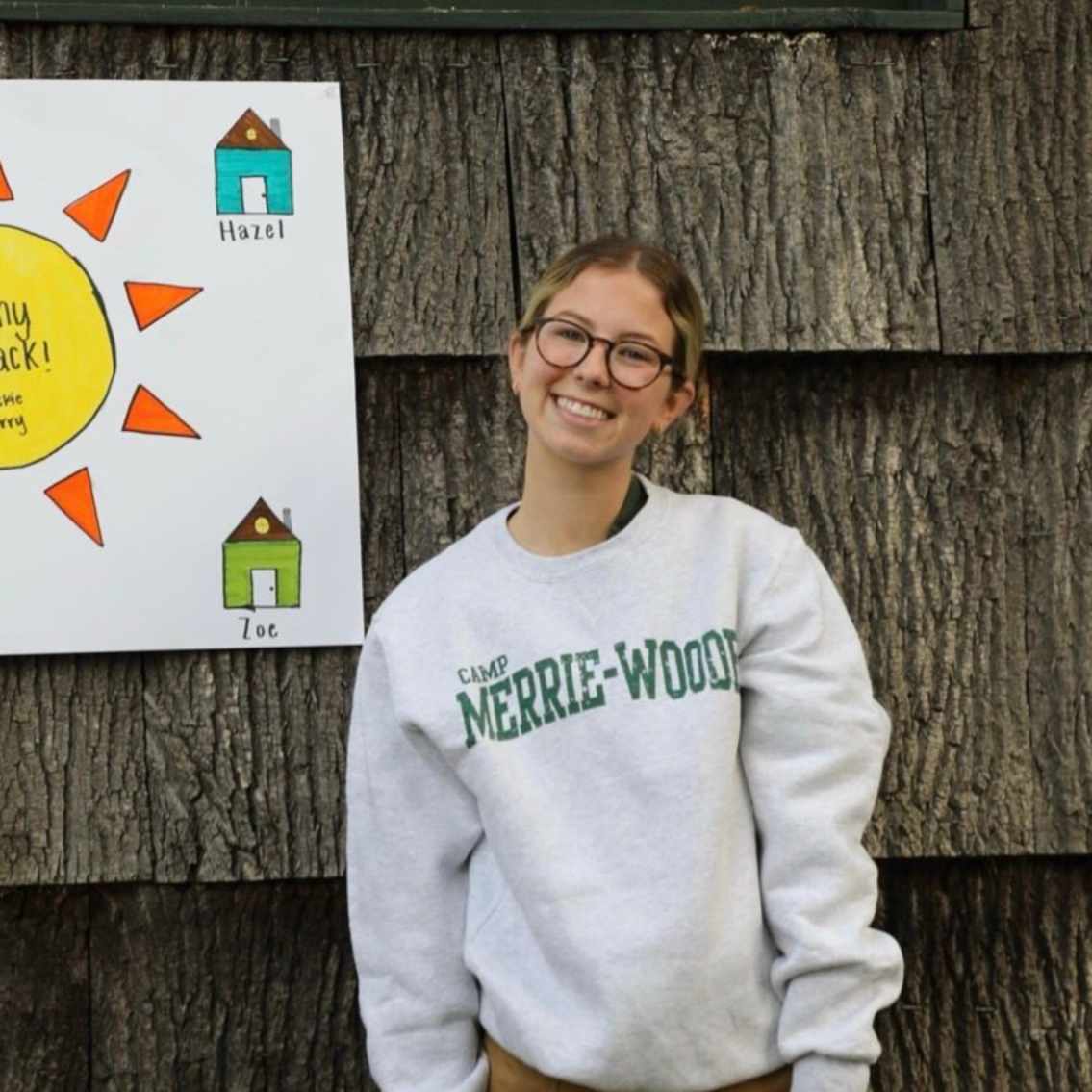 A smiling person wearing glasses and a 