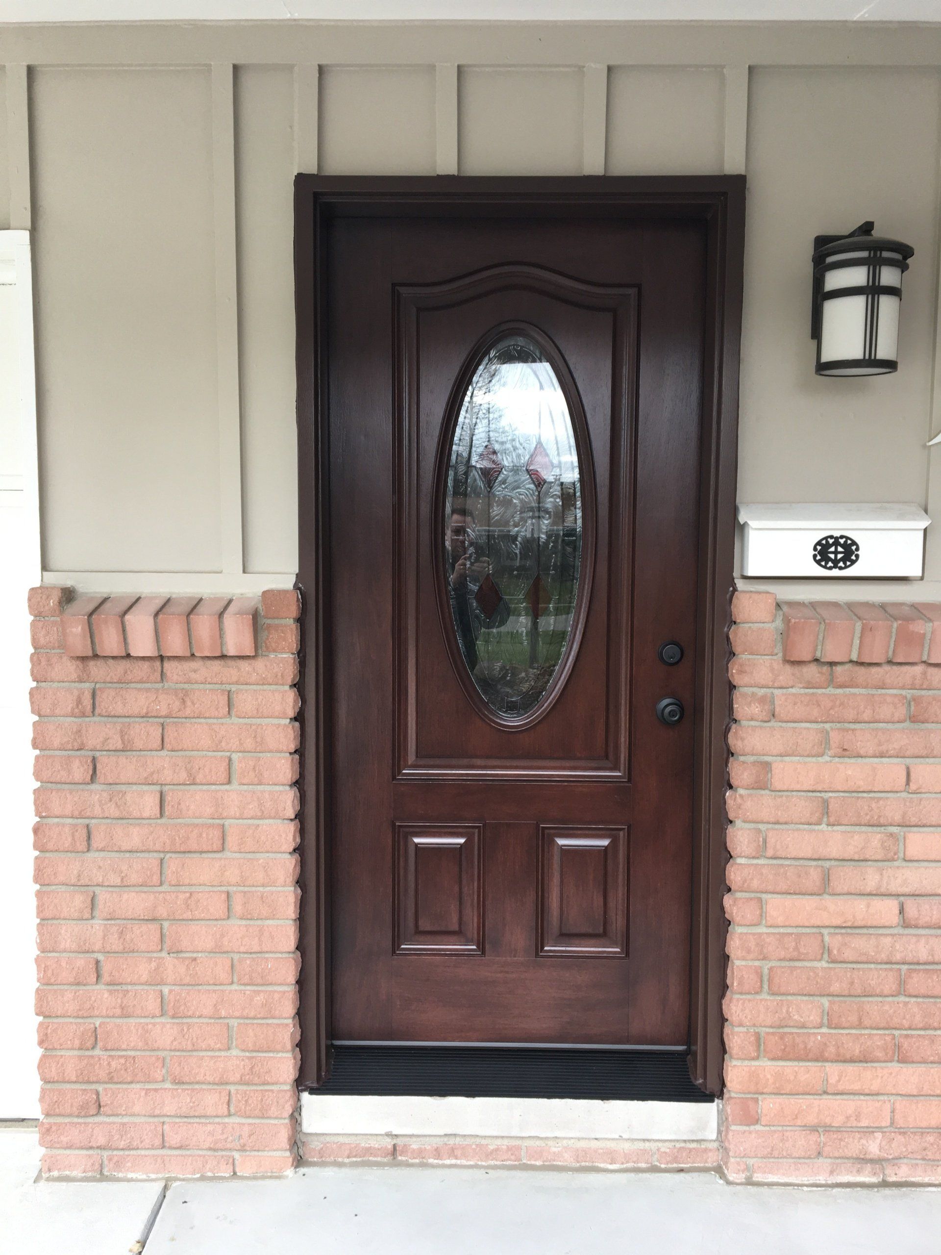 The front door of a house with a brick wall and a wooden door