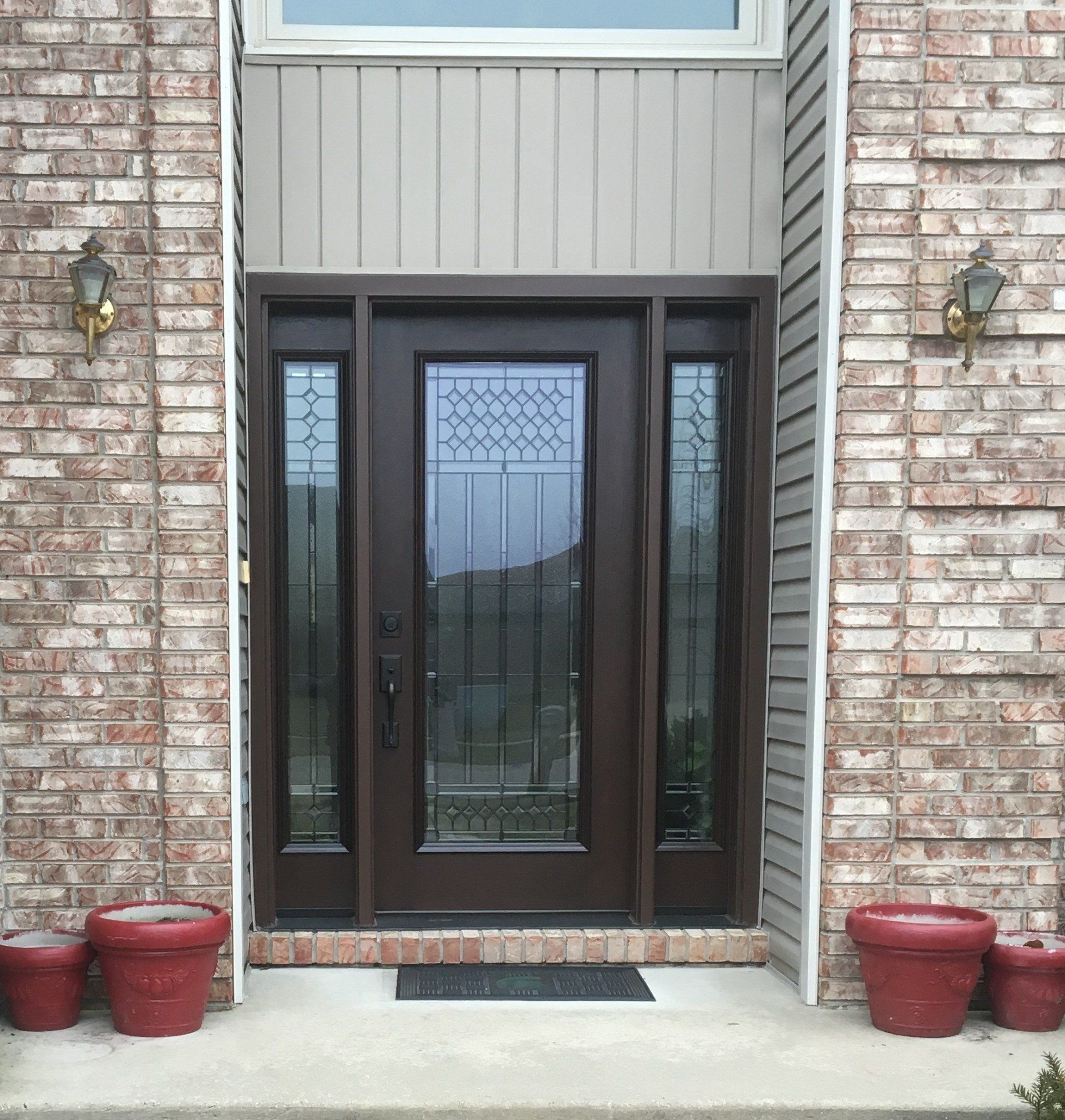 The front door of a brick house with a brown door